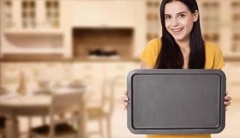 Kitchen woman gives empty tray for your advertising products at home in the kitchen. Mock up for use photo