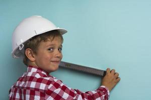 un chico lindo con una camisa a cuadros sostiene un nivel de construcción en sus manos, un retrato de un pequeño constructor foto