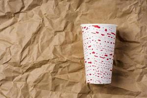 Creative minimalistic composition, paper cup on the background of crumpled wrapping paper, coffee, tea, ecology concepts photo