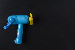 blue toy fan with manual drive on a black background, space for copying photo