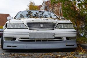 An old classic Japanese car in an autumn urban landscape, popular sedan made in Japan parking on city urban street photo