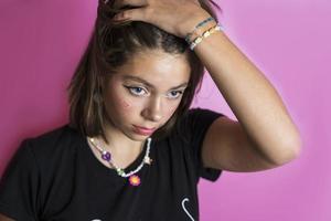 Portrait of a beautiful Caucasian girl shaking her hair, posing on a pink background photo