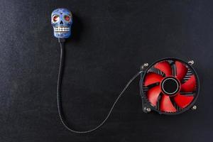 Creative composition, a computer cooler connected to a skull on a black background photo