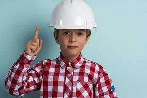 un chico lindo en un casco de construcción protege su cabeza, un retrato de un pequeño constructor en un casco foto