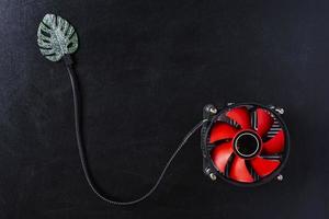 Creative composition, computer cooler connected to a green leaf on a black background, the concept of ecology photo