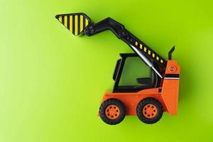 Orange Toy Loader on Green background, Mini Loader, Toy Industrial Car, Plastic Front Wheel Loader photo