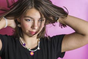 retrato de una hermosa chica caucásica sacudiendo su cabello, posando sobre un fondo rosa foto