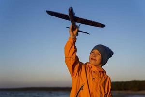 Portrait of a cute boy holding a plane in his hand against a blue sky, the path to a dream, the road to the sky photo