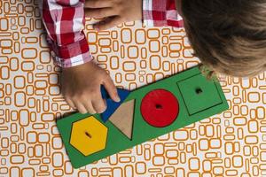 The child collects the sorter constructor. Puzzle sorter, an early development concept. Children's hands put the puzzle photo