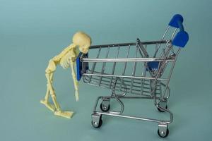 creative minimalist composition, a skeleton riding on a supermarket cart, turquoise background, a skull photo