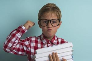 A boy with glasses, with books in his hands on a turquoise background. Knowledge is power, Back to school. photo