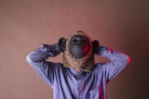 an annoyed old man in a monkey mask holding his head, photo