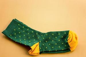 Green socks with yellow polka dots. A pair of socks on a beige background. photo