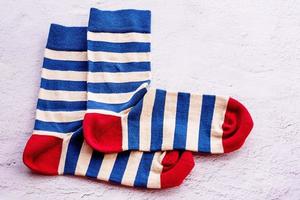 A pair of socks on a gray cement background. Blue and beige striped socks with a red toe and heel. photo