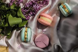 pink and mint french macaroons or macarons cookies and a lilac flowers on a cloth background. Natural fruit and berry flavors, creamy stuffing for valentines mother day easter with love food