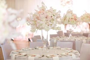 decoración festiva de la boda. hermosas flores blancas y rosas frescas en un jarrón de vidrio en la mesa del comedor el día de la boda. foto de alta calidad