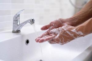 las manos de la persona se lavan con burbujas de jabón y se enjuagan con agua limpia para prevenir y detener la propagación de gérmenes, virus o covid-19. buena salud y buena higiene foto