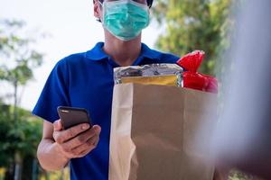 The delivery man wears a mask to prevent the spread of germs and send the goods or food that the buyer order online on the website. Ordering products online or ordering food online photo