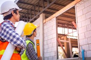 The contractor and engineer stood to inspect the house construction. After agreeing the price of work and calculating the cost of construction and repair of real estate. photo