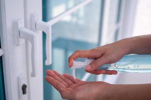 Female using a hand wash alcohol gel to prevent the infectious disease before going in and out the door. Concept of prevention of disease spread. photo