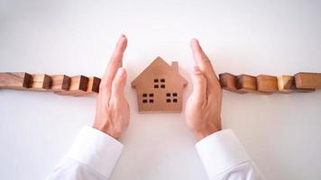 insurance with hands protect a house. Home insurance or house insurance concept photo