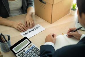 la mujer de negocios tiene una caja de cartón marrón al lado de su cuerpo y envía una carta de renuncia al jefe del empleador. incluir información sobre la renuncia al trabajo y las vacantes. foto