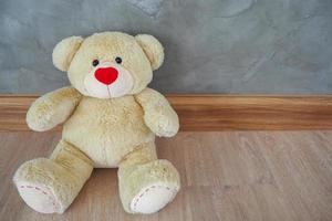Teddy bear sitting against a gray wall in the house. Gifts for children photo