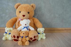 A group of teddy bears sitting on wooden floor at home. On special occasions for surprise. photo