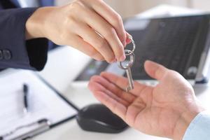 The new home owner receives the house key from the salesperson. photo