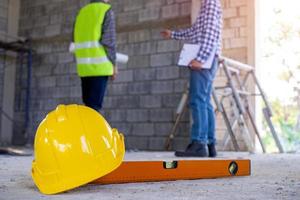 primer plano del sombrero amarillo y el nivel del agua. los inspectores verifican la integridad de la construcción de la casa. discutir métodos y resolver problemas con los contratistas. foto