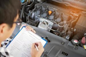 The car mechanic working in the car garage is checking the engine. photo