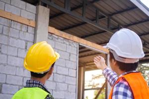 The inspector is checking with the checklist and pointing out the new building with the structure and materials used to the customer or client. Inspection and engineering concept photo