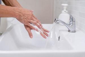 Person hands wash with soap bubbles and rinse with clean water to prevent and stop the spread of germs, virus or covid-19. Good health and good hygiene photo