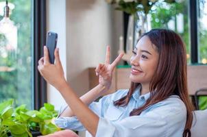 hermosas y lindas mujeres asiáticas usan el teléfono para tomar una selfie. las mujeres son felices y disfrutan tomando fotos. la relajación de una mujer en edades 20-30 años foto