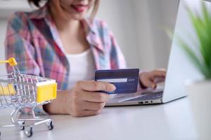 mujer comprando en línea pagando con tarjeta de crédito. conveniencia de gastar sin efectivo. manténgase seguro, comprando desde casa y distancia social foto