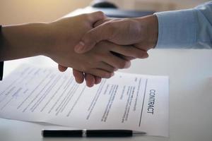 Two businessmen join hands to sign a contract. Joint venture to do business together photo