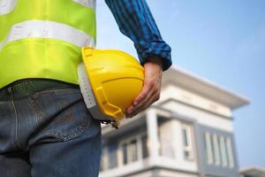 Construction staff holding a hard hat with an external house built photo