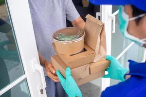 The shipper wears a mask and gloves, delivering food to the home of the online buyer. stay at home reduce the spread of the covid-19 virus. The sender has a service to deliver products or food quickly