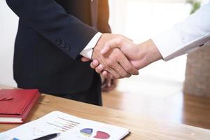 Businessmen join hands to invest and share profits in real estate projects. On the table, there are documents and historical performance data. photo