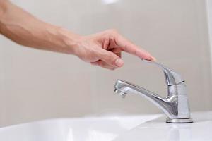 The faucet in the bathroom with running water. Man keeps turning off the water to save water energy and protect the environment. save water concept photo