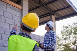 The inspectors are examining the structure of the house and note it in the clipboard to inform engineers to fix before selling to customers. photo