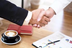 Businessmen join hands to invest and share profits in real estate projects. On the table, there are documents and historical performance data. photo