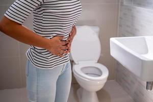 estreñimiento y diarrea en el baño. mujer lastimada tocar vientre dolor de estómago doloroso. problema de inflamación del colon, alimentos tóxicos, dolor abdominal, abdomen, estreñimiento en el inodoro, dolor de estómago, higiene foto