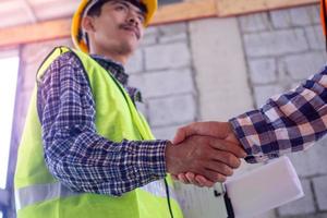 Hand in hand between project contractors and customers due to negotiation of expenses and investments, construction and repair of residential buildings. photo