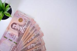 cierre los nuevos billetes de 1000 baht, alineados en una mesa de estilo tailandés. conceptos de moneda del banco tailandés o de la nota tailandesa foto