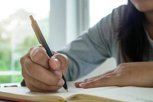 The hand of a black woman holding a pen and writing right hand. business or education concept photo