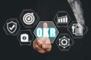 OKR, Objectives and Key Results concept, Business person hand touching Objectives and Key Results icon on virtual screen, Methods for project management. photo