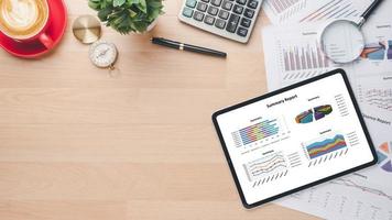 Tablet with charts and reports on office desk workplace. Top view flat lay photo