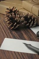 cajas de regalo envueltas en papel reciclado y tarjetas de regalo, cajas de regalo de año nuevo colocadas sobre una mesa de madera, un espacio de copia y una caja de regalo de navidad marrón. foto