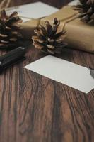 cajas de regalo envueltas en papel reciclado y tarjetas de regalo, cajas de regalo de año nuevo colocadas sobre una mesa de madera, un espacio de copia y una caja de regalo de navidad marrón. foto